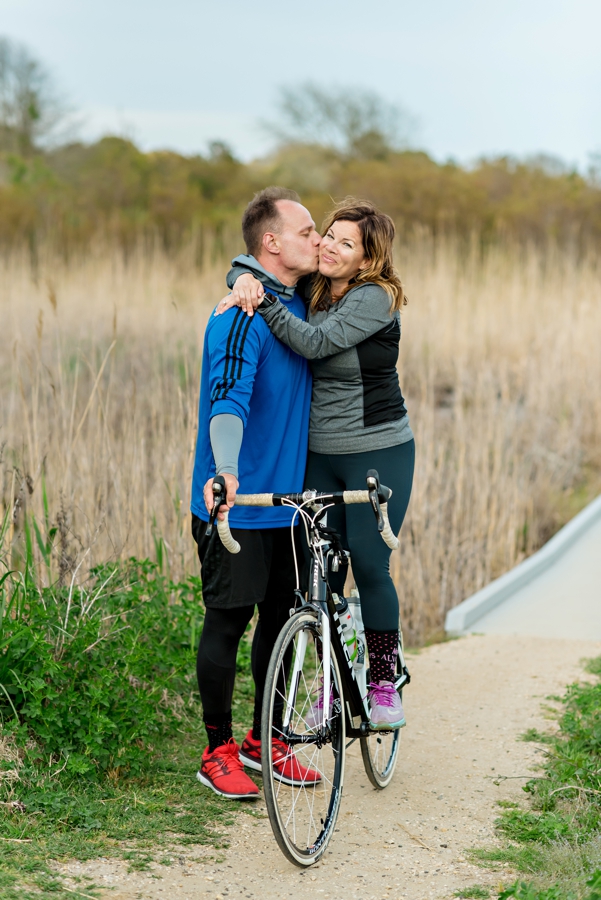 A man kissing his fiance while she sits on her bike in cape may, nj.